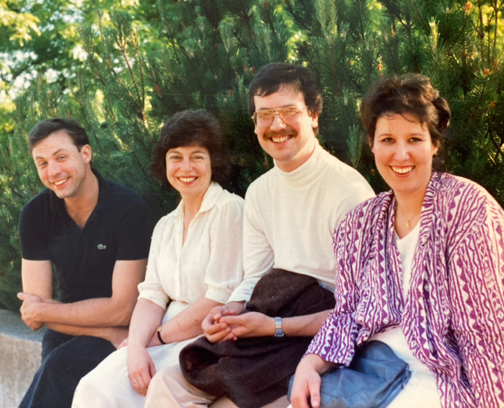 Four college-age students (two men and two women) smiling, in 1986.